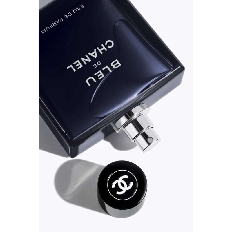 A transparent glass perfume bottle with a black cap, featuring the Bleu de Chanel logo. The bottle contains Bleu de Chanel Eau de Toilette 100ML.